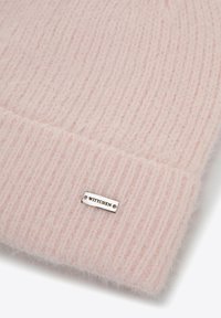 Měkká růžová pletená čepice s žebrovanou texturou. Na ohybu má malou stříbrnou značku s nápisem "WITCHEN".