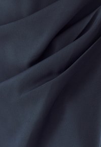 Tmavo námorníková látka s hladkou, matnou textúrou, obsahujúca jemné záhyby a drapérie, ktoré naznačujú ohybnosť a mäkkosť.