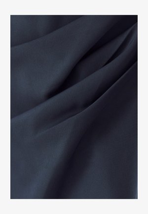 Tmavě námořnická tkanina s hladkým matným povrchem, s jemnými záhyby a sklady, naznačujícími ohebnost a měkkost.