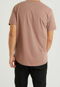 Krátký rukáv, tričko s kulatým výstřihem v barvě prašné růže, vyrobené z jemné bavlny, s malým logem na zadní straně a ohrnutými manžetami.