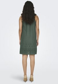 Zelena haljina bez rukava s opuštenim krojem, koja ima izvezene cvjetne uzorke duž rubova i glatku, laganu teksturu.