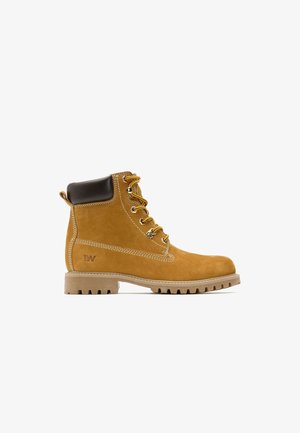 Stivale alla caviglia in suede beige con colletto imbottito marrone, lacci gialli, cuciture bianche e suola in gomma robusta con un motivo di battistrada distintivo.