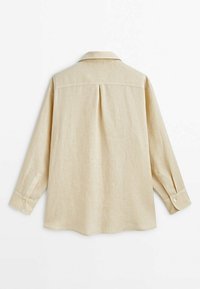 Chemise beige à manches longues avec un pli central dans le dos, des poignets boutonnés et un col classique, présentée à plat sur fond blanc.