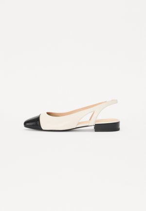 Cipele s remenom, s kremastom gornjom polovinom i crnim sjajnim vrhom. Imaju nisku blok petu i izrezane detalje sa strane.