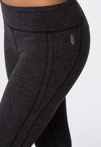 Leggings de sport noirs avec une taille haute, dotés d'un tissu texturé, de détails de coutures contrastées et d'un petit logo sur la cuisse.