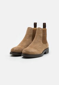 Brown suede Chelsea boots with elastic side panels, rounded toe, and pull tabs. Rubber sole provides traction and stability.