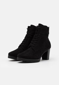 Schwarze Wildleder-Stiefeletten mit einem hohen Blockabsatz, die vorn mit Schnürung, strukturiertem Obermaterial und minimalen Nähten ausgestattet sind.