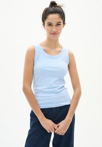 Hele sinine ribikuga tank top, millel on lai krae ja ilma varrukateta disain, koos tume denimpükstega.