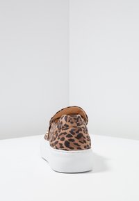 Hausschuh im Leopardenmuster mit gepolstertem Kragen, strukturiertem Stoff und weißer Plateausohle; enthält goldfarbene Akzente an der Seite.