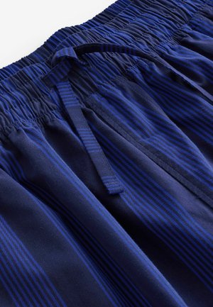 N�ámořnické modré šortky vyrobené z měkké tkaniny, které mají vertikální pruhy v různých odstínech modré, elastický pas a šňůrku na stažení.