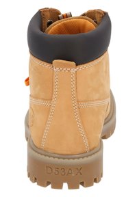 Bota de cuero marrón claro con un cuello acolchado negro, suela texturizada, acento naranja, costuras visibles y un logotipo en relieve en el lateral.