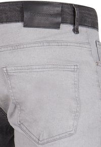Grå denim jeans med en svart midjebånd, med en lærmerke merket "27 PREMIUM," og en enkelt baklomme med subtil søm.