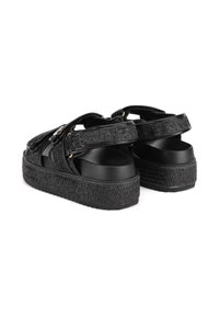 Las sandalias de plataforma negras cuentan con correas texturizadas, una base de dedo suave y suelas elevadas con un patrón tejido. Se presentan detalles de hardware.