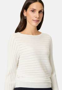 Weißer Strickpullover mit geripptem Design und vertikalen Streifen, langen Ärmeln und rundem Ausschnitt.