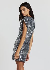 Silbernes Pailletten-Minikleid mit kurzen Ärmeln und figurbetonter Silhouette. Es zeichnet sich durch eine strukturierte Oberfläche und ein glattes, glänzendes Finish aus.