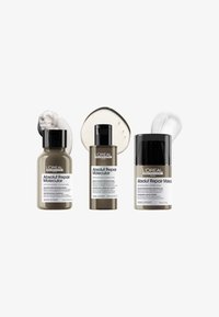 Tre L'Oréal hårvårdsprodukter: ett schampo, ett serum och en leave-in-behandling, alla i bruna glasflaskor med svarta lock och etiketter.