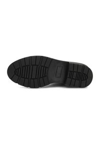 Suela de zapato de goma negra con un patrón texturizado, que presenta crestas y surcos para ofrecer tracción, diseño plano y bordes lisos.