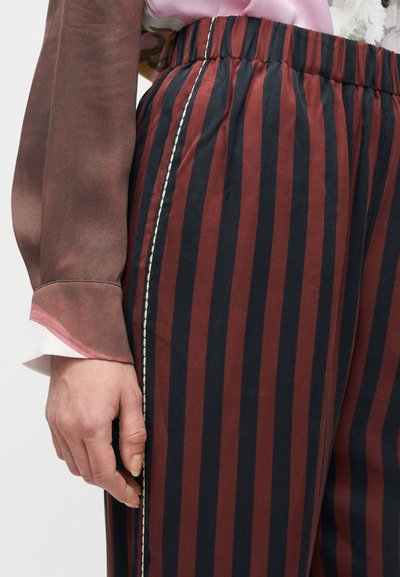 Pruhované nohavice v bordovej a námorníckej modrej farbe, s elastickým pásom a kontrastným bielym prešívaním pozdĺž bočného švu.