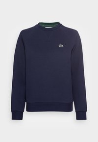 Sweatshirt bleu marine en mélange de coton. Présente un col ras du cou côtelé, des manches raglan, et un petit logo crocodile vert sur la poitrine.
