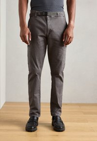 Sivé slim-fit nohavice s pútkami na opasok, bočn�ými zipsami a prednými vreckami. Vyrobené z odolného materiálu, s hladkou textúrou a minimálnym prešitím.