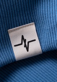 Blue ribbed fabric featuring a white textile label with a black heartbeat graphic. The design is smooth with clear textures and contrasting colors.