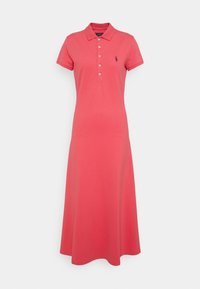 Sukienka polo z koralowego bawełnianego materiału. Posiada kołnierzyk, zapięcie na guziki oraz wyszywane logo na piersi. Rozszerzana linia hemu.