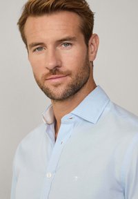 Lichtblauw button-up shirt met een witte geborduurde logo, gestreepte textuur en contrasterende, van patroon voorziene binnenkraag. Regular fit en gemaakt van katoen.