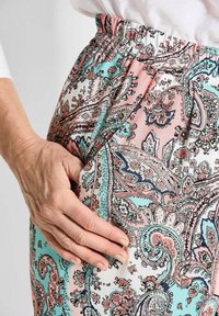 Jupe à taille élastique à motifs dans des couleurs pastel, présentant des motifs paisley complexes avec des tons corail, turquoise et blancs ; tissu léger.