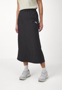 Schwarze lange Skirt mit einem elastischen Bund, mit weißem Puma-Logo-Akzent. Hergestellt aus glattem, strapazierfähigem Stoff, hat sie eine gerade Silhouette.