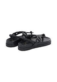 Sorte sandaler med tekstureret stropdesign, der har en polstret ankelrem og runde metalaccent på en flad sål.