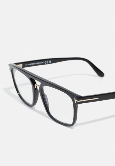Óculos de plástico pretos com uma armação retangular, apresentando detalhes em dourado nas hastes e lentes transparentes. Design minimalista.