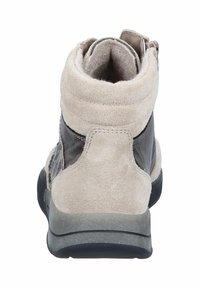 Beige suede ankle boot with black leather accents, rounded toe, and textured back. Features minimal stitching and a slip-resistant sole.