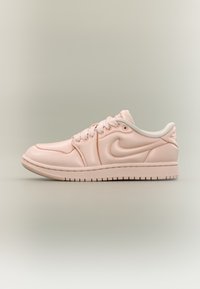 Baskets Nike rose clair en matériau synthétique lisse, bout arrondi, accents blancs, lacets, et semelle texturée.