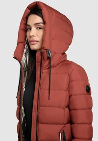 Red puffer jacket with a hood, featuring a shiny silver lining, zippered pockets, and elastic drawstrings for adjustment. Textured quilted pattern.