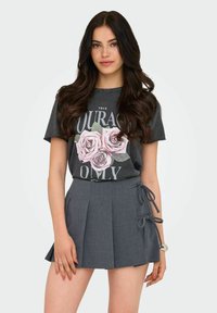 Camiseta gráfica gris con print de rosas rosas, combinada con una falda plisada gris oscuro con lazos laterales. Tejido suave, diseño casual.