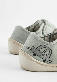 Graue Stoffschuhe mit einer hellbeigen Gummisohle verfügen über ein gesticktes Autodesign an der Seite und haben ein kariertes Futter.