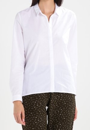 Camisa blanca de manga larga con botones, cuello puntiagudo y dobladillo recto. Tela de algodón suave con tapeta delantera y puños.