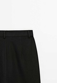 Jupe noire avec passants de ceinture et détail de couture verticale sur fond blanc.