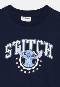 T-shirt de algodão azul marinho com uma estampa do Stitch da Disney, com texto em branco e azul claro a dizer "STITCH" e detalhes em estrela prateada.