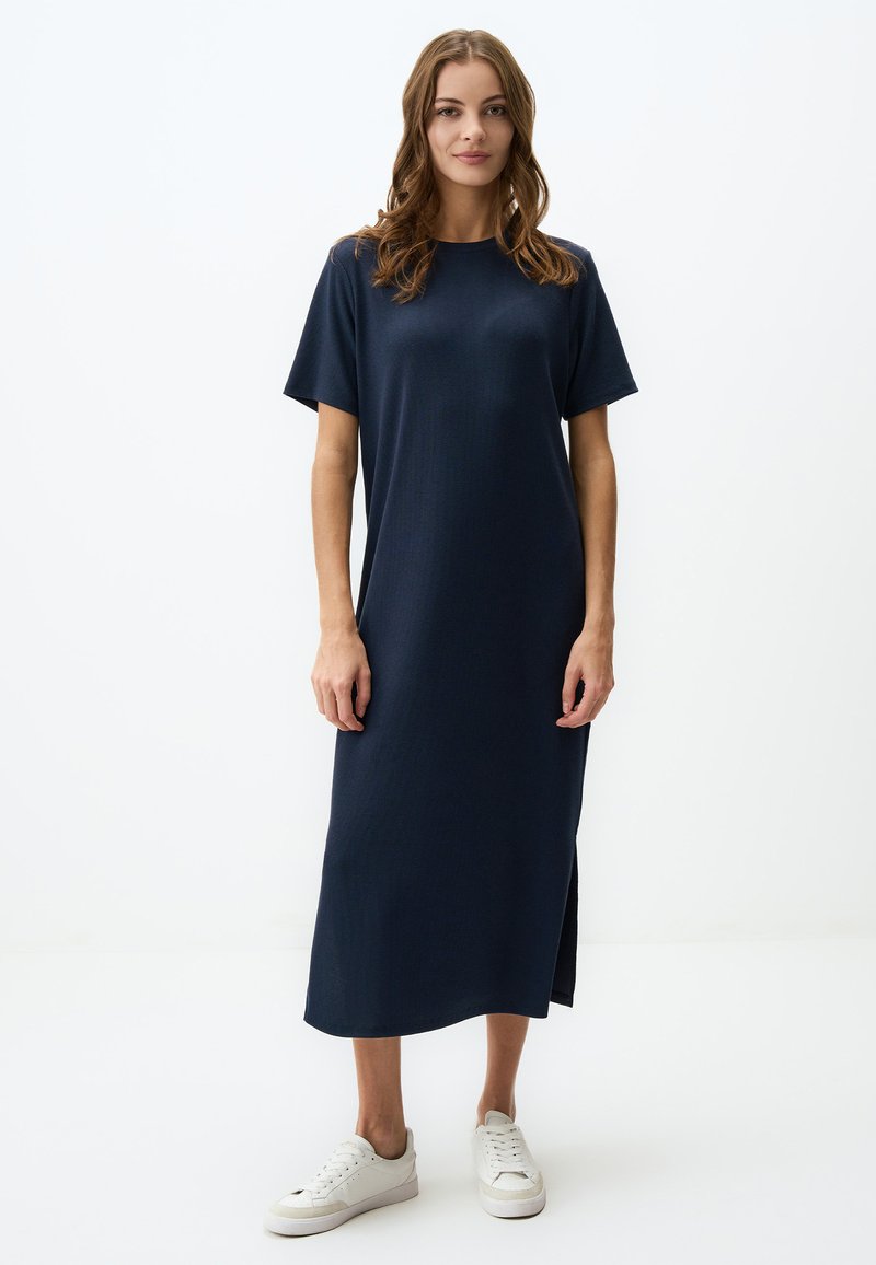Abito midi a coste blu navy con maniche corte e spacchi laterali, abbinato a sneakers bianche. Realizzato in un tessuto liscio e leggero.