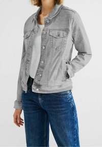 Světlý šedý denimový kabát s zapínáním na knoflíky, klasickým límcem a dvěma kapsami na prsou. Má prošité švy a mírně ošoupanou strukturu.