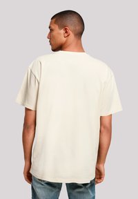 Beige cotton T-shirt with a relaxed fit, short sleeves, and a crew neck, featuring a smooth texture and no visible patterns or accents.