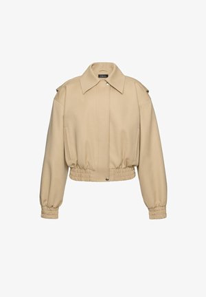 Beež kahepoolne jakk laiema kraega, elastse ääre ja mansettide, eesmist kinnitust neetidega ja külgpilu taskutega.