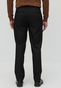 Zwarte broek met een rechte snit, voorzien van een gladde textuur, twee achterzakken en ceintuurlussen, gecombineerd met gepolijste zwarte schoenen.