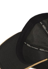 Casquette noire avec intérieur en maille, visière plate et dessous beige. Présente une étiquette logo le long de la couture intérieure. Détails en tissu texturé.