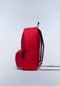 Röd ryggsäck med en slät nylonutsida, justerbara svarta remmar, sidoficka och minimalistisk design. Har ett handtag på toppen för bärande.