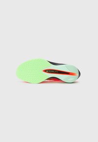 Nike Flyplate shoe sole features a flexible green rubber outsole with a textured pattern, a black midsole, and bold orange accents.