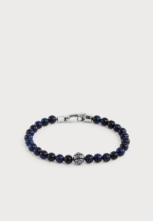 Bracelet à perles avec des perles bleu foncé et noires alternées, un fermoir en argent et une perle centrale en argent gravée avec "GUESS."