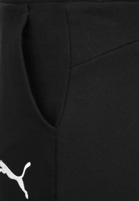 Shorts atléticos negros con una suave mezcla de algodón, bolsillo en ángulo y un acento de logo blanco en la parte delantera inferior.
