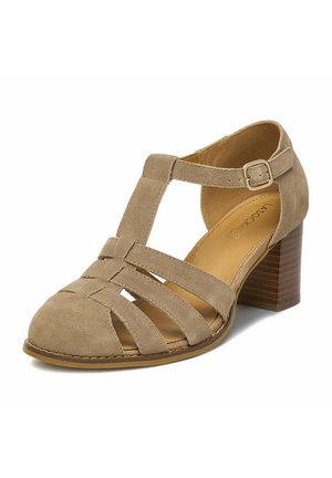 Dámská béžová semišová sandála s pevnou podrážkou, uzavřenou špičkou s T-páskem a několika překříženými pásky, a nastavitelnou přezkou.